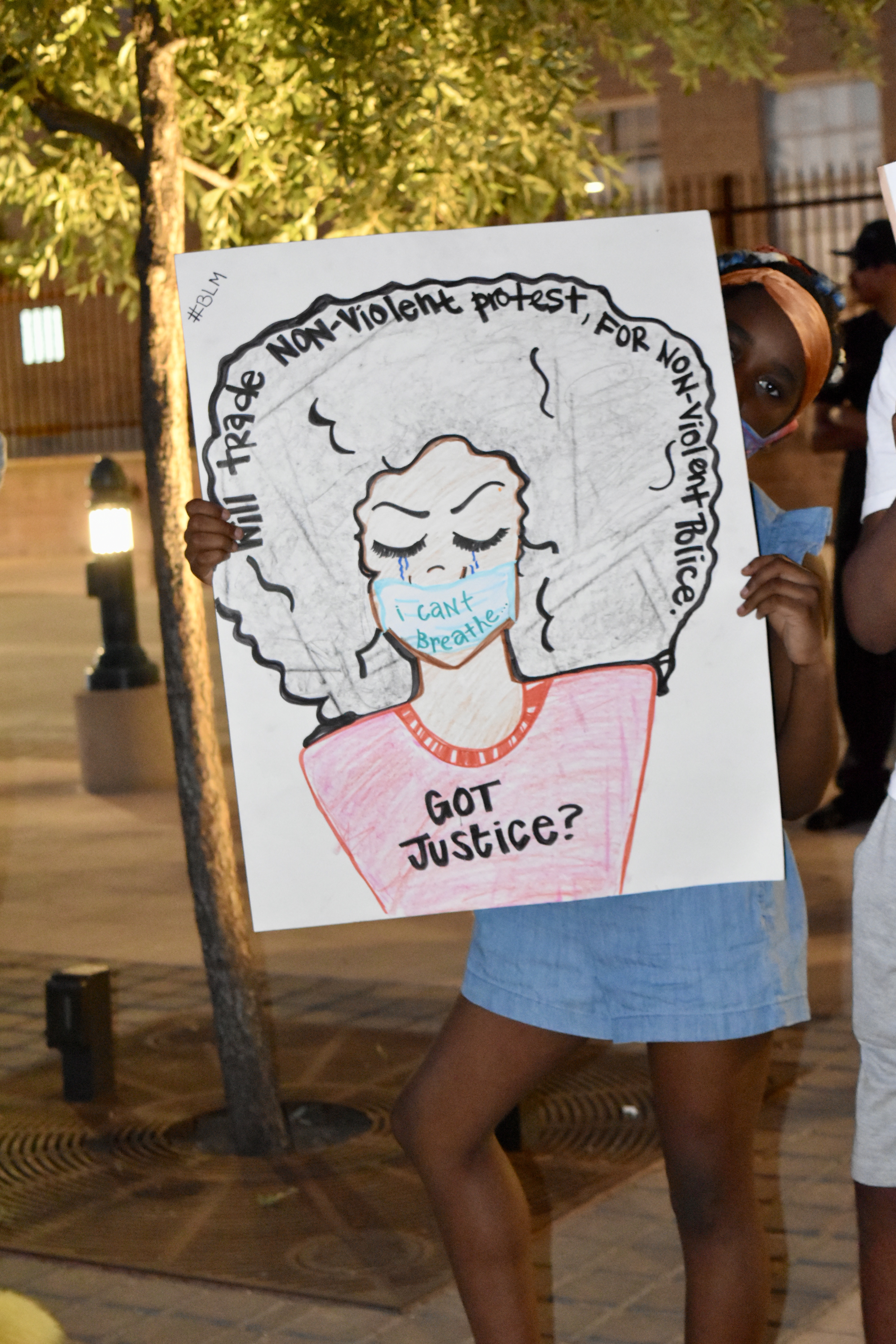 Attendee holding a hand drawn picture of a women with the text on the sign reading "Black Lives Matter"